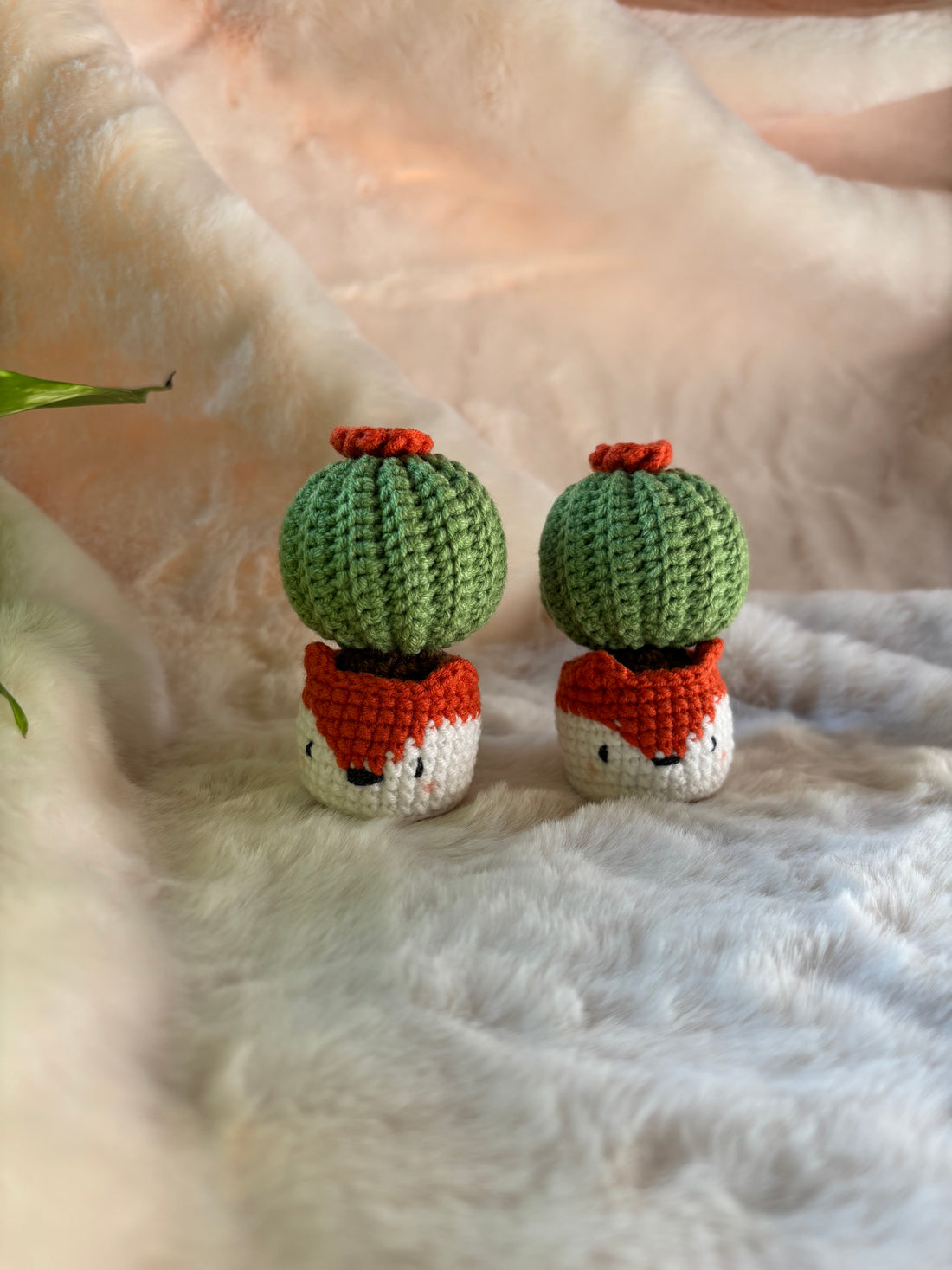 Two crochet cacti with orange flowers in fox pots