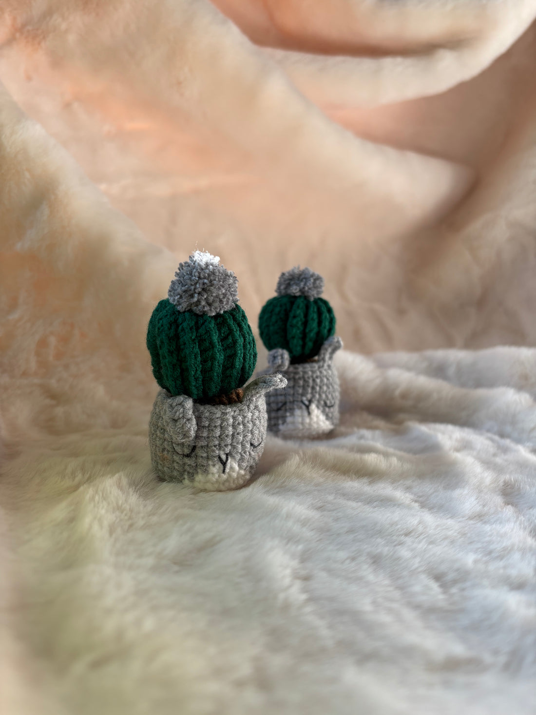 Crochet cacti in grey cat pots standing side by side