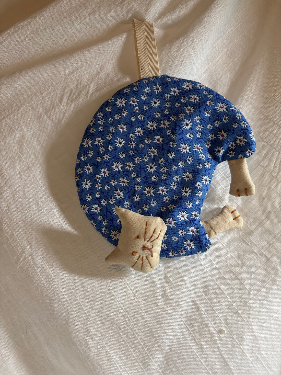 Close-up of a hand-embroidered cat face on a fabric potholder