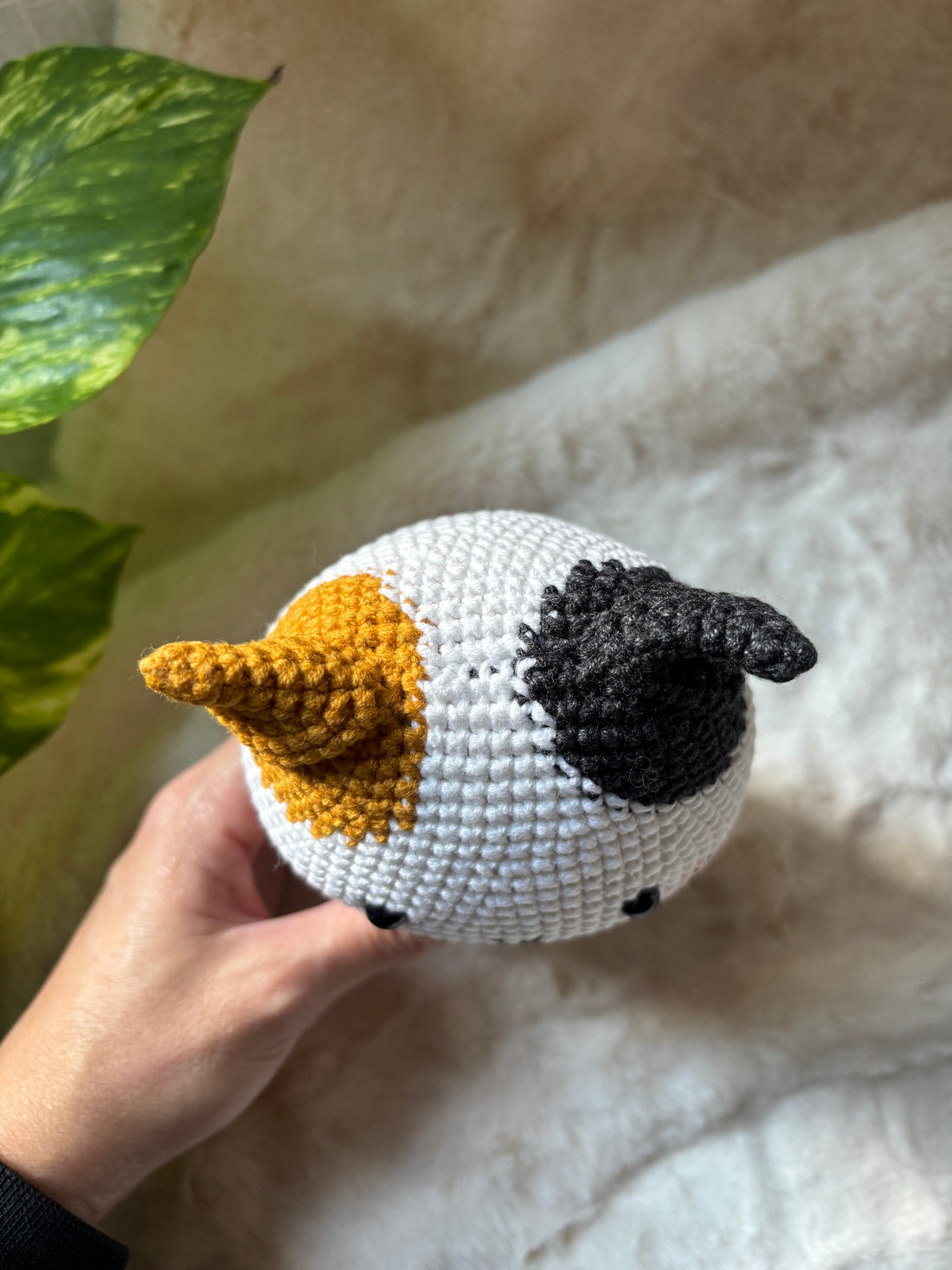 Crochet calico cat lying down, showing orange and black patches