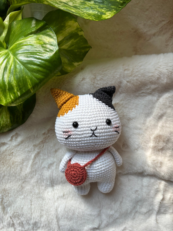 Crochet calico cat with orange and black ears and red bag