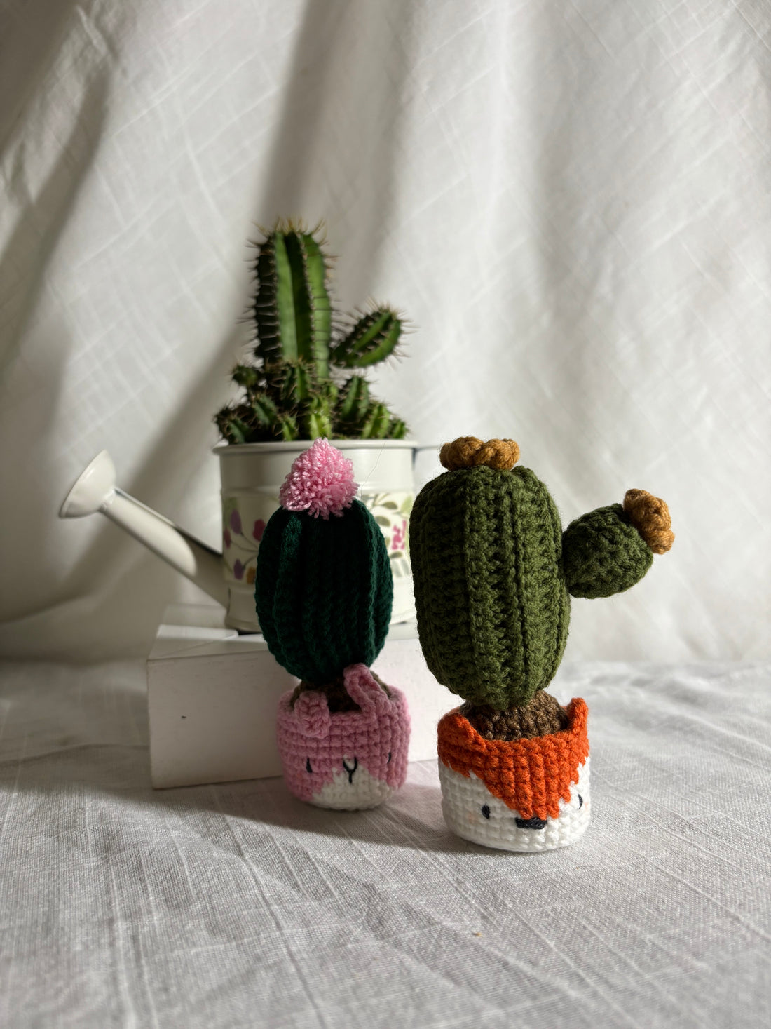 Two crochet cacti with yellow and pink flowers in animal pots