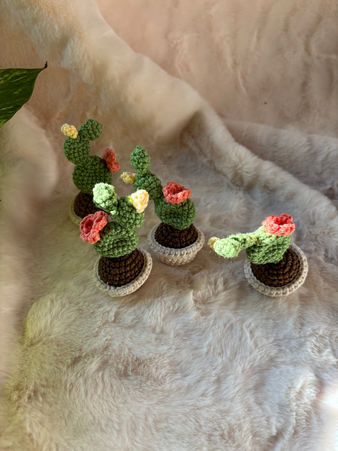 Set of four tiny crochet prickly pear cacti with coral and yellow flowers
