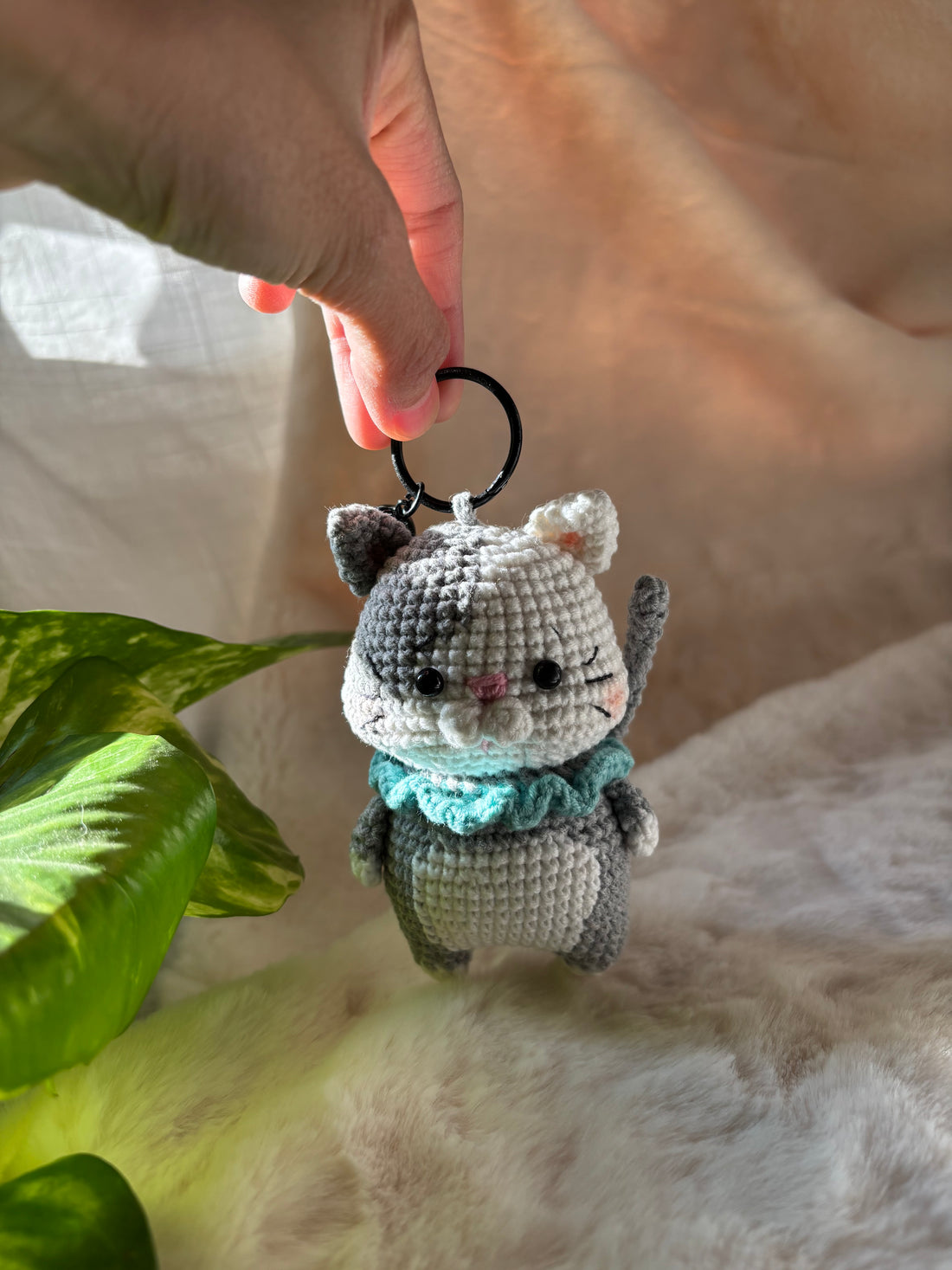 Crochet kitten keychain held up to show its pink nose