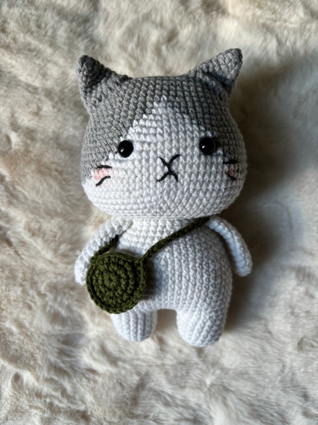 Close-up of crochet grey cat face with whiskers and rosy cheeks
