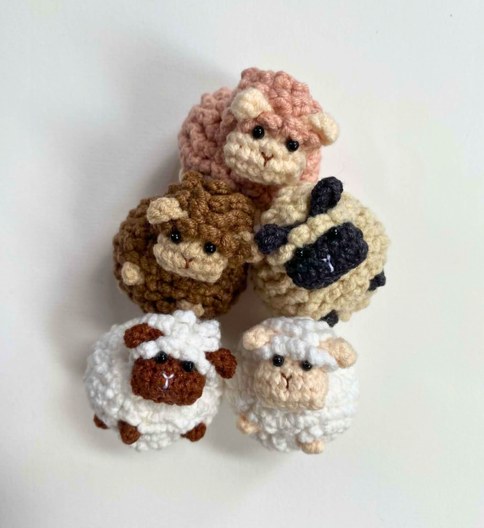 Five crochet sheep party favours in pink, brown, cream, white and white with brown face