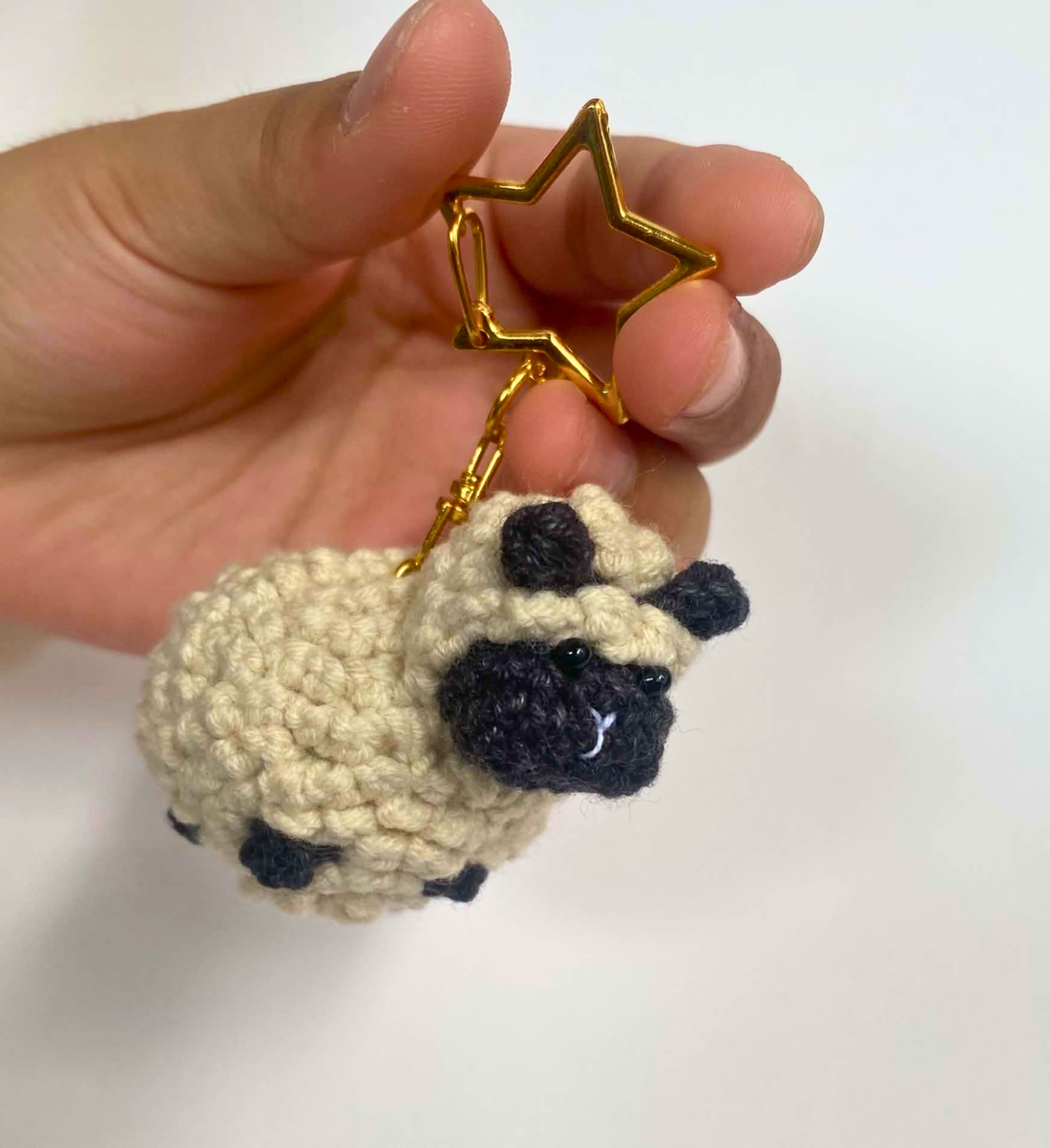 Cream crochet sheep keychain with black face and gold star clasp