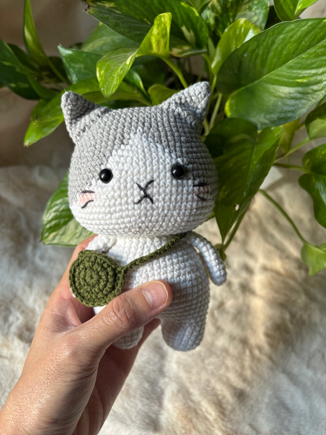 Crochet grey cat held in a hand to show its 15 cm size