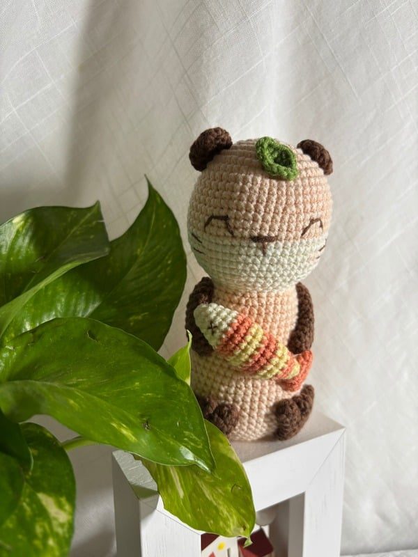 Crocheted peach otter holding a striped fish