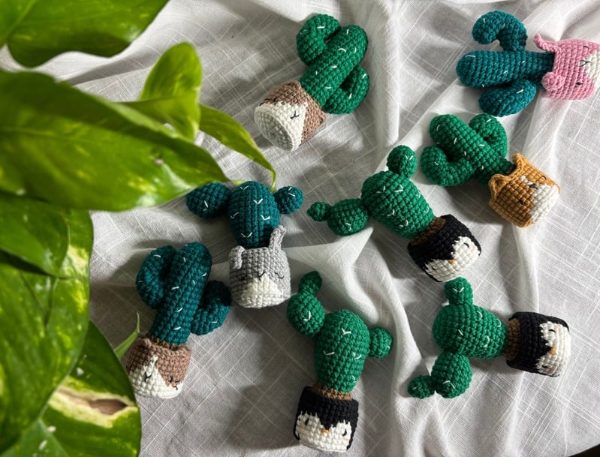 Eight crocheted cacti in pots with sleepy animal faces