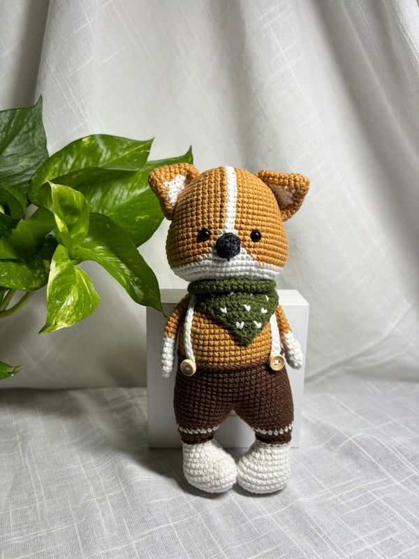 Crocheted shiba dog in brown overalls and a green bandana